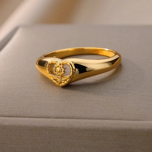 Detailed close-up of a gold-plated ring with hollow heart and floral motif on display