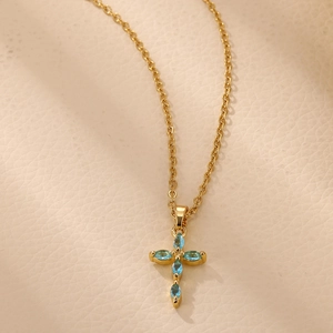 Detalle del collar chapado en oro 18K con pequeño colgante de cruz de piedras azules