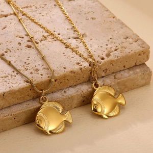 18K gold plated fish pendant necklaces on travertine stone in minimalist aesthetic