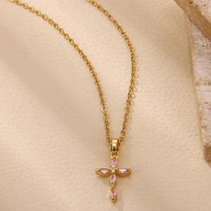 Detalle de collar con colgante de cruz bañada en oro 18K con piedras rosadas de marquesa
