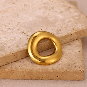 Detailed close-up of a polished gold geometric sun brooch on natural travertine stone