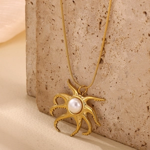 Detailed close-up of a 18k gold-plated octopus pendant with white pearl on stone