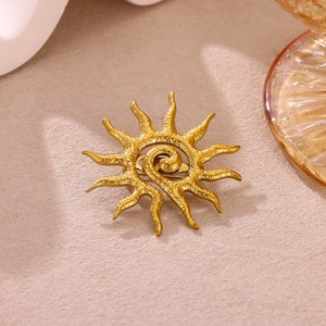 Vintage golden sunburst brooch with spiral core and textured rays on neutral backdrop