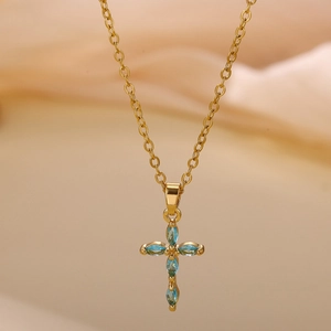 Detalle macro del colgante de cruz chapado en oro con circonitas azul mar talla marquise