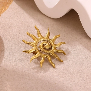 Macro detail of sun-shaped gold brooch showing spiraled center and radiant metal texture