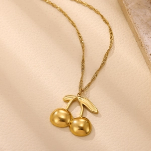 Close-up of a 18k gold-plated cherry pendant on a twisted water wave chain over leather