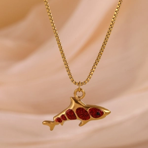 Detail of shark pendant necklace with red glitter filling on golden stainless steel box chain