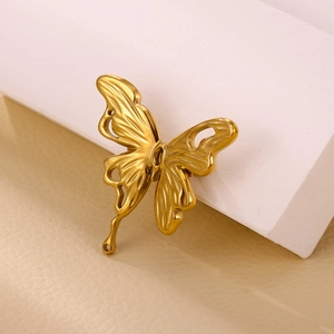 Elegant vintage matte gold butterfly brooch with hollow wings on white stone base
