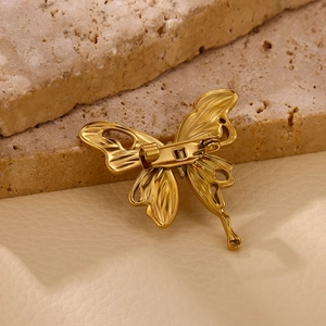 Detailed back view of a gold butterfly brooch showing the secure pin clasp and metal texture