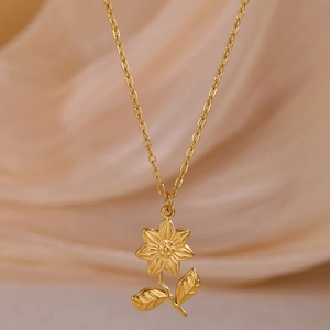 Macro shot of gold flower pendant necklace with leaf texture on beige silk background