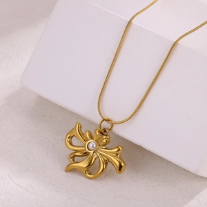Macro shot of gold-plated 18k bow pendant with pearl on a sleek snake chain
