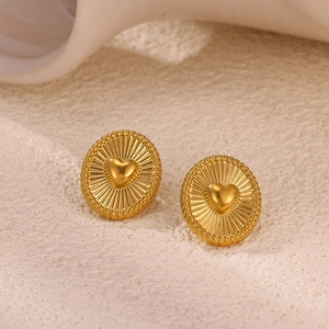 Macro detail van vergulde ovale oorbellen met 3D hart en stralend zonnemotief patroon