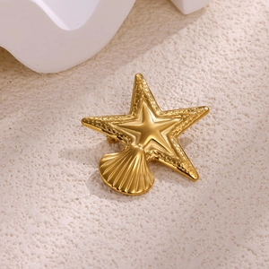 Macro shot of elegant golden starfish and seashell brooch with textured metallic finish