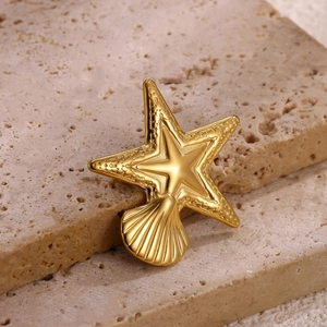 Macro shot of gold-plated starfish and scallop brooch detailing on natural stone
