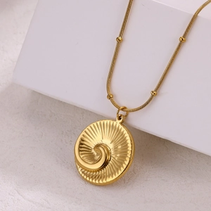 Detail of 18k gold plated spiral pendant with beaded snake chain on geometric stand