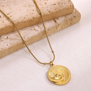 Detail of 18k gold plated sunburst pendant necklace on texture stone background