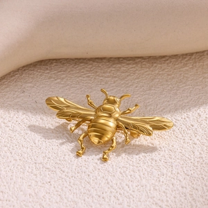 Detailed view of the gold bee brooch showing the wings' texture and metallic finish
