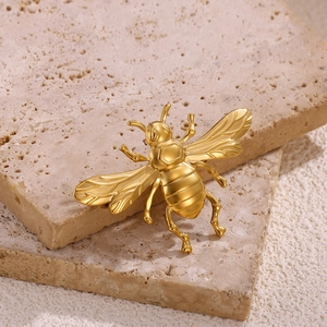 Detailed macro view of a golden bee brooch featuring hexagonal honeycomb texture and wings