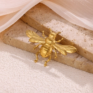 Detailed macro shot of a golden bee brooch with textured wings on stone and tulle fabric