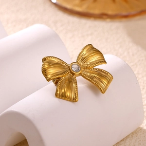 Detailed view of a gold-plated bow brooch with textured finish and center crystal accent