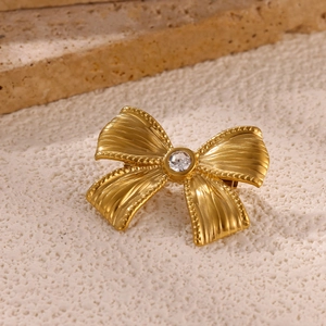 Macro detail of gold-plated sun-shaped brooch with sparkling crystal on stone background