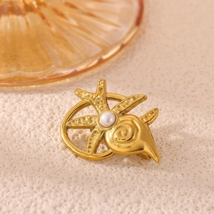 Detailed macro view of gold sunburst brooch featuring conch, starfish, and pearl inlay