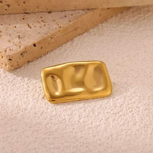 Macro shot of gold sun brooch featuring irregular liquid metal texture on travertine stone