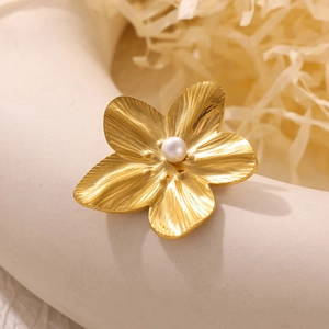 Macro shot of gold sun flower brooch with brushed metal petals and center white pearl