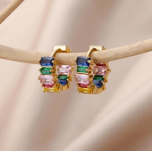 Rainbow rectangle zircon huggie earrings in gold finish hanging on a wooden branch