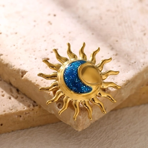 Macro shot of gold sun and blue glitter moon celestial brooch on textured stone background
