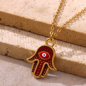 Detail of Hamsa pendant with red enamel, evil eye design on golden O-chain over stone