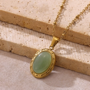 Détail d'un collier vintage doré avec pendentif en pierre verte ovale et perles