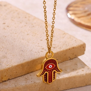 Detailed close-up of golden Hamsa Hand pendant with red enamel and lucky evil eye charm