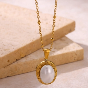 Détail d'un collier doré en acier inoxydable avec pendentif perle ovale sur pierre