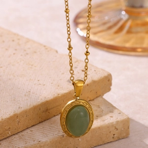 Détails d'un collier pendentif ovale doré avec pierre verte et accents de perles imitation