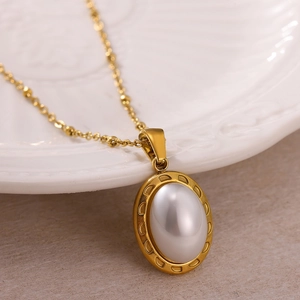 Vue détaillée du collier doré avec pendentif ovale en pierre blanche sur une assiette