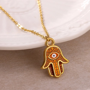 Close-up of golden Hamsa Hand pendant with Evil Eye detail and orange patterns