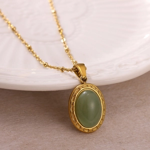 Détail d'un collier vintage doré avec pendentif pierre ovale verte sur plateau