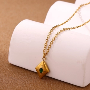 Detail of bohemian gold stainless steel necklace with green gemstone in diamond pendant