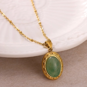 Collier vintage doré avec pendentif ovale en pierre verte sur une assiette en porcelaine