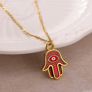 Detailed close-up of a Hamsa Hand pendant with red enamel and lucky eye on a gold chain