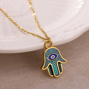 Detailed macro view of the Hamsa Hand pendant with blue Evil Eye and golden chain texture
