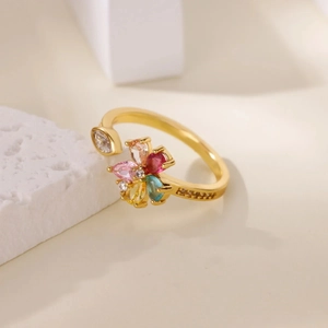 Dettaglio dell'anello aperto a fiore con zirconi colorati su fondo in marmo