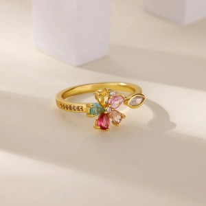 Dettaglio macro di un anello a fiore in zircone colorato con petali multicolori e banda oro