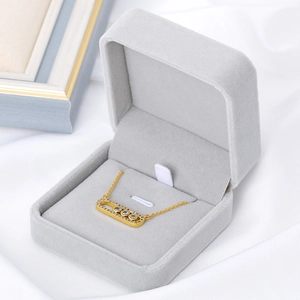 Gros plan d'un pendentif doré à diamants mobiles dans son écrin de luxe en velours gris
