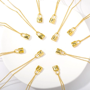 Polished gold stainless steel padlock pendant necklaces with engraved letters A-Z on white stand