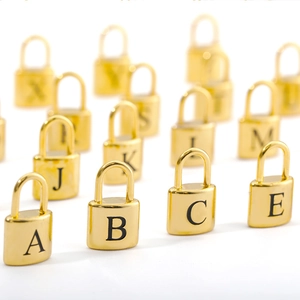 Close-up of polished gold padlock pendants featuring engraved black capital letters