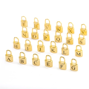 Detailed macro view of gold-plated stainless steel padlock pendants with engraved letters
