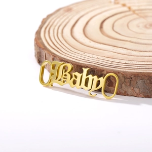 Détail de la breloque de chaussure dorée en acier inoxydable Baby sur bois naturel