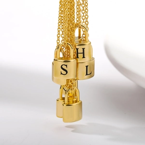 Detail view of gold lock pendants with black engraved letters on polished metal chains